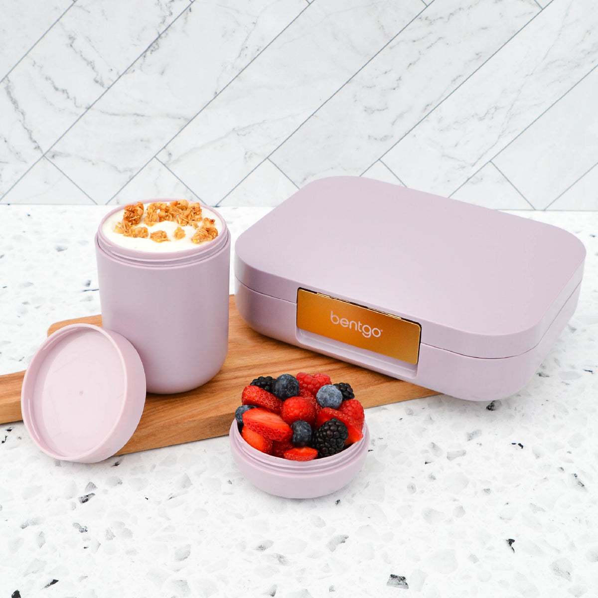 Purple Bentgo lunch box with compartments filled with snacks on a marble surface